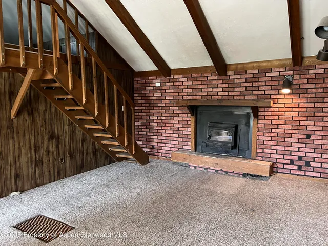 a view of an empty room with wooden floor and a fireplace