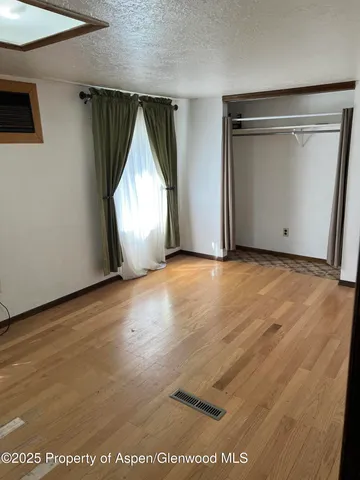 an empty room with wooden floor garage and window