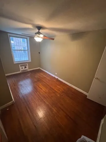 an empty room with wooden floor ceiling fan and windows