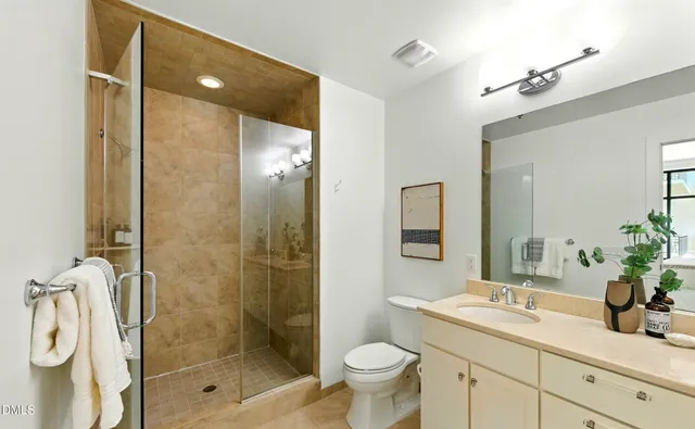 a bathroom with a shower sink vanity mirror and toilet