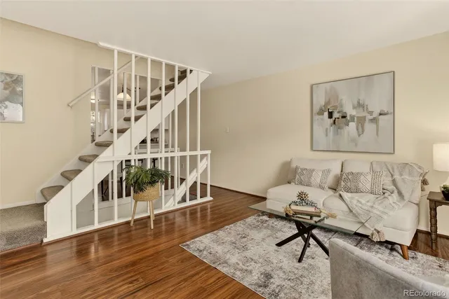 a living room with couches and a dining table with wooden floor