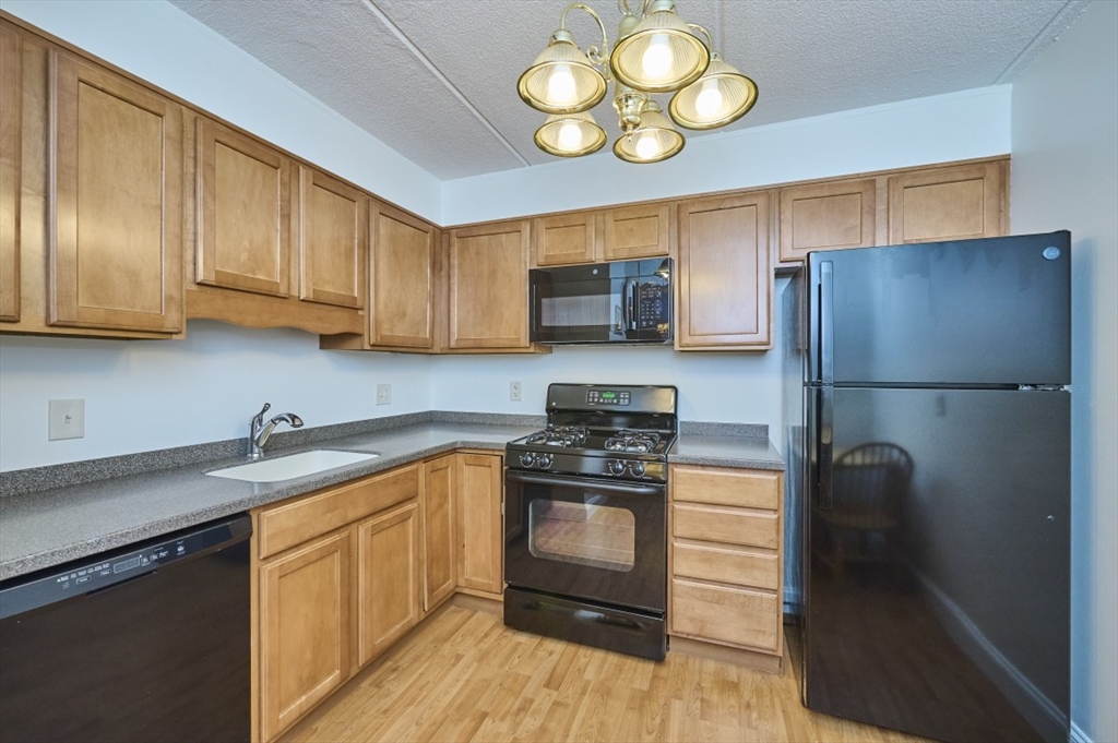 1500 Worcester Road, Unit 612 Framingham, MA 01702 - Photo 7 of 17 a kitchen with a refrigerator and a sink