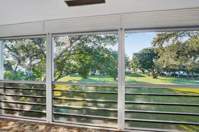 a patio with a table and chairs under an umbrella with palm trees
