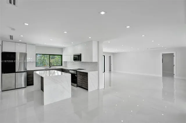 a view of a kitchen with kitchen island a sink wooden floor and a refrigerator
