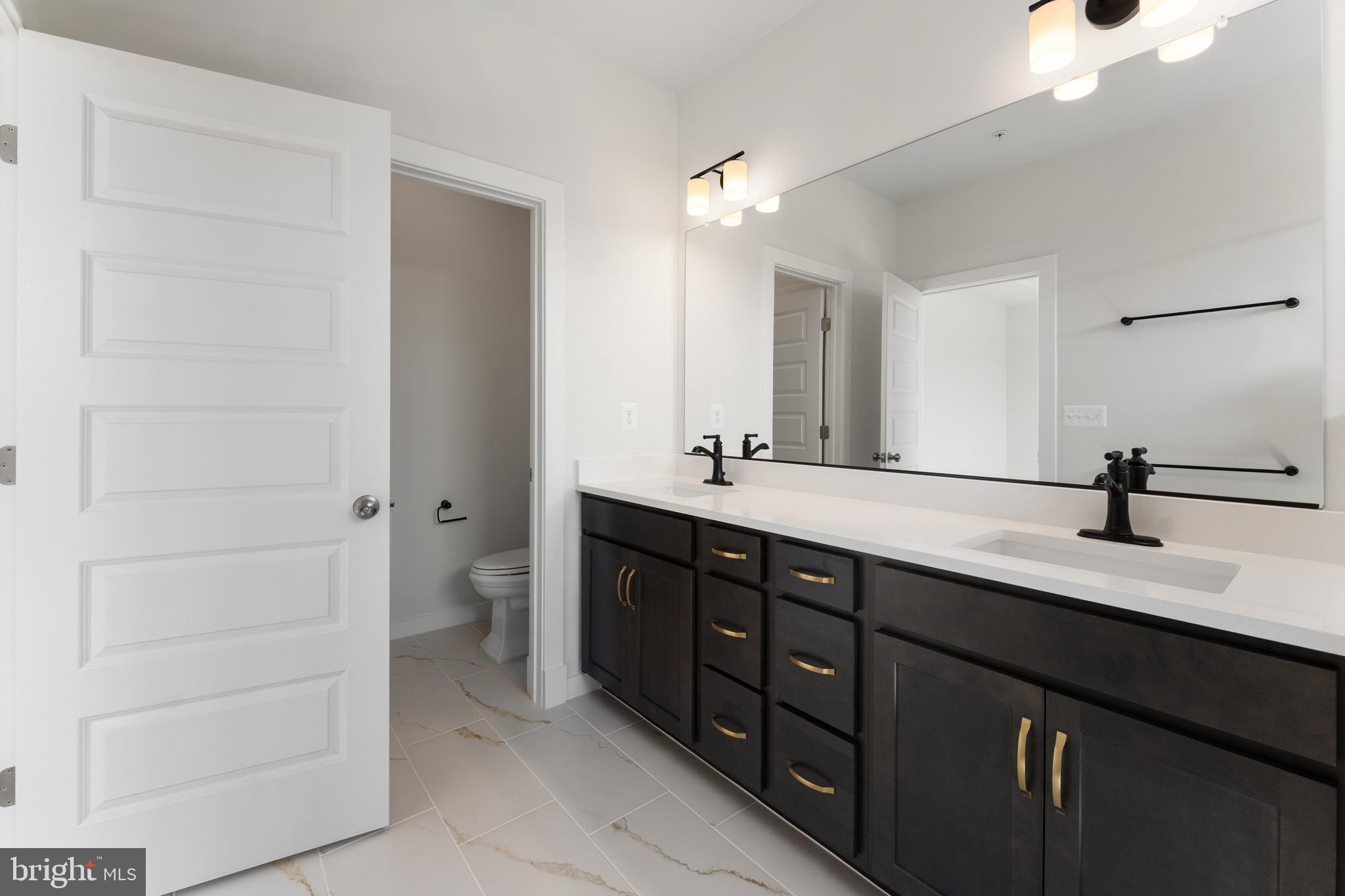 113 Summit Point Boulevard, Unit 19J Bowie, MD 20716 - Photo 19 of 38 a bathroom with a double vanity sink a and a mirror