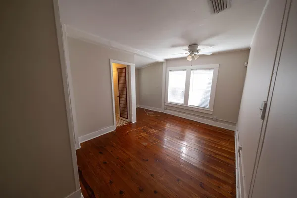 an empty room with wooden floor chandelier and windows