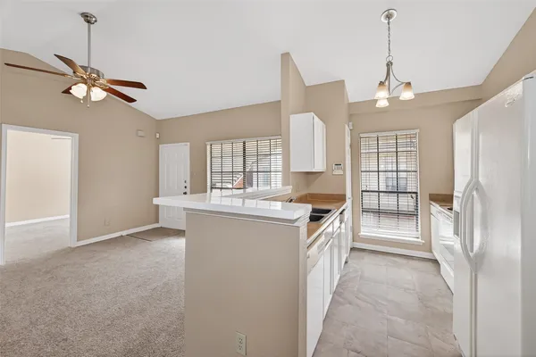 an empty room with chandelier fan and windows