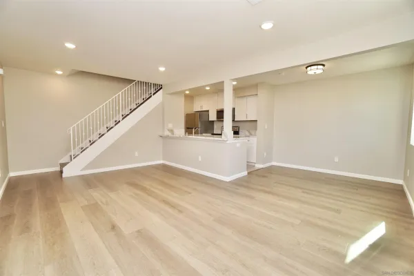 a view of an empty room with wooden floor and stairs
