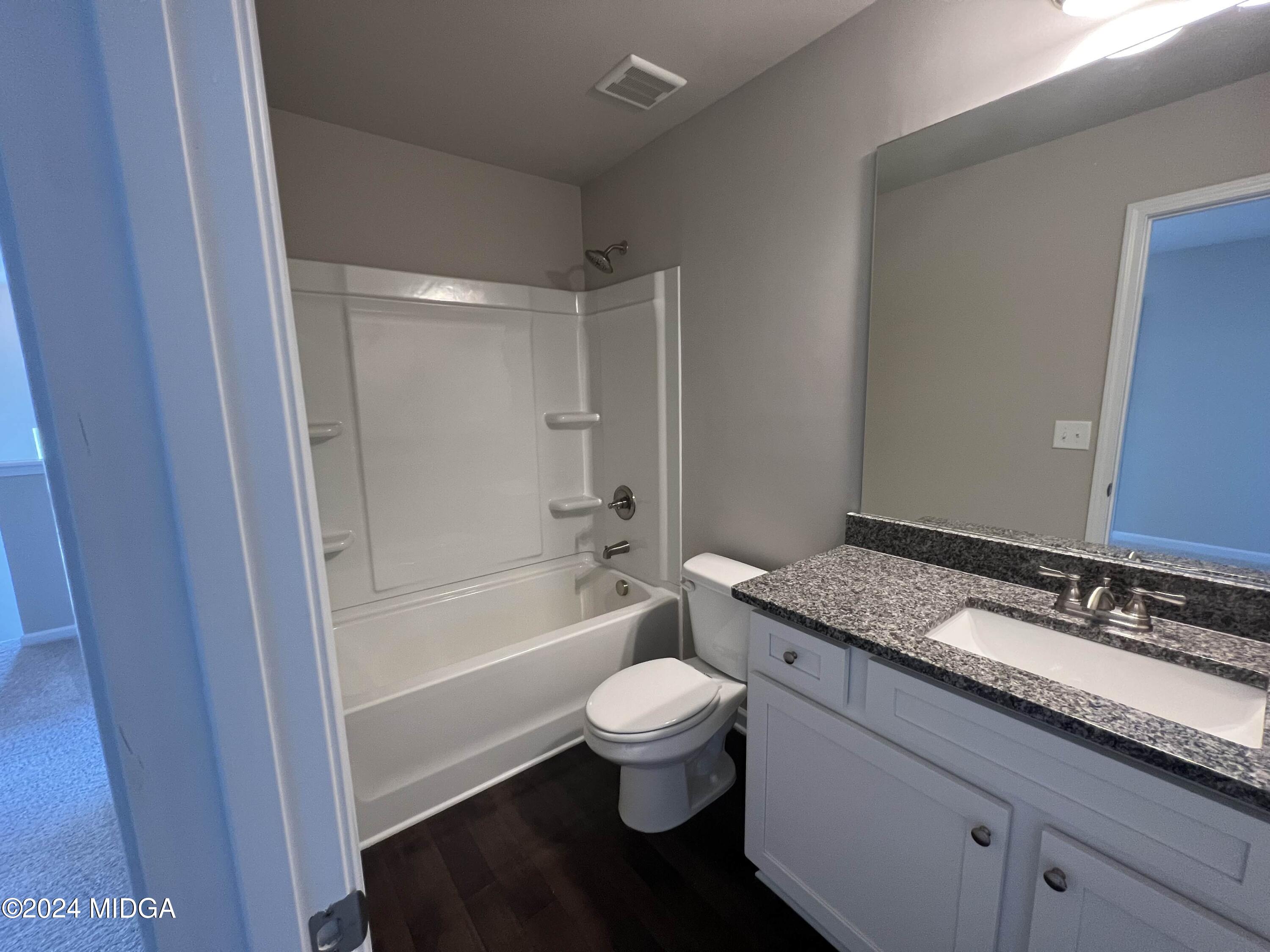 183 Sanders Road Macon, GA 31210 - Photo 32 of 44 a bathroom with a granite countertop toilet a sink and a bathtub