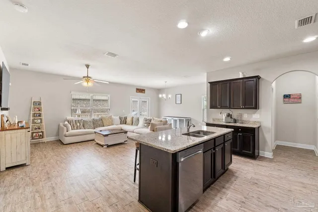 a kitchen with stainless steel appliances granite countertop a stove top oven a refrigerator a sink and a dining table with chairs