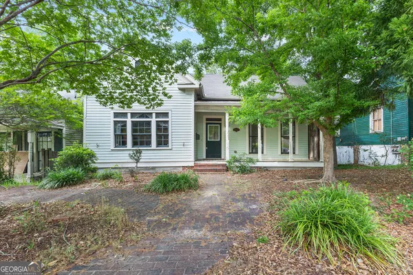 a front view of a house with garden and trees