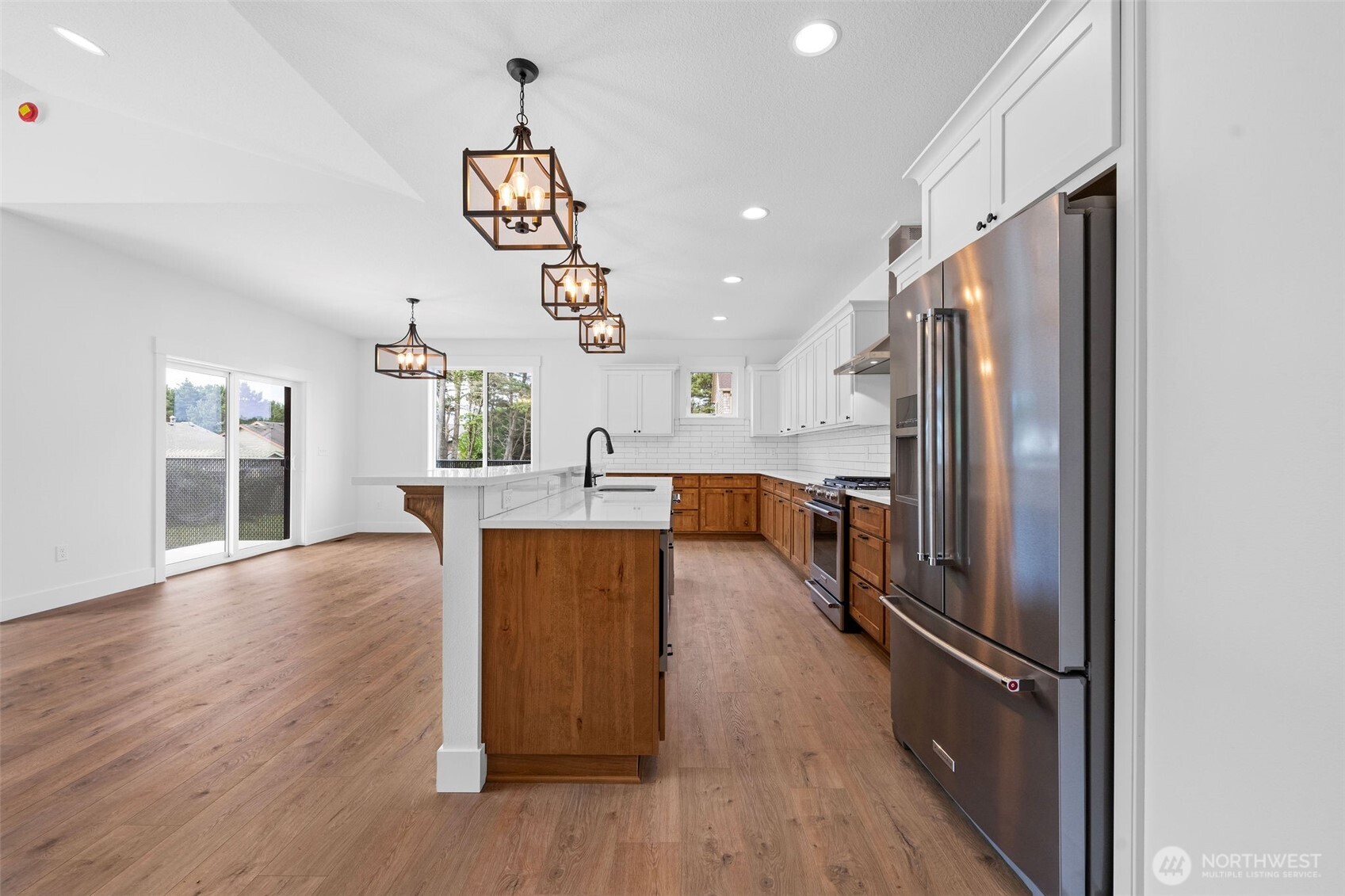 1306 195th Street Long Beach, WA 98631 - Photo 5 of 24 a kitchen with stainless steel appliances granite countertop a refrigerator a sink dishwasher a stove and a dining table with wooden floor