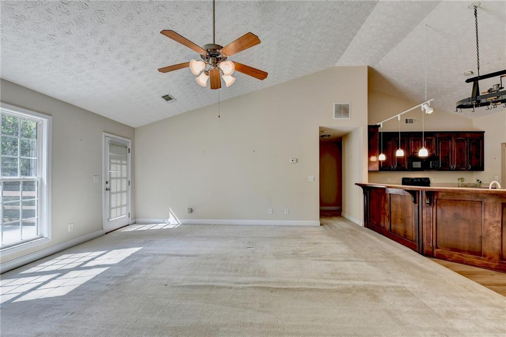 52 Katie Spring Lane Jefferson, GA 30549 - Photo 33 of 57 a view of an empty room with a ceiling fan and a kitchen