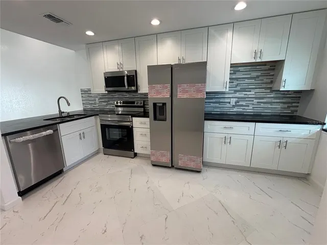 a kitchen with granite countertop a sink stainless steel appliances and cabinets