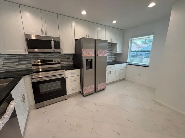 a kitchen with stainless steel appliances a stove a microwave and white cabinets