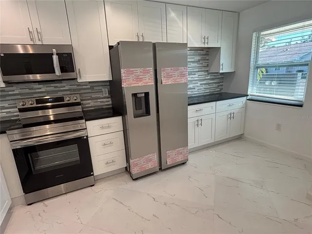 a kitchen with granite countertop a stove microwave and refrigerator