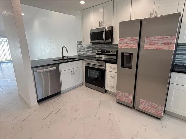 a kitchen with stainless steel appliances a refrigerator sink and microwave