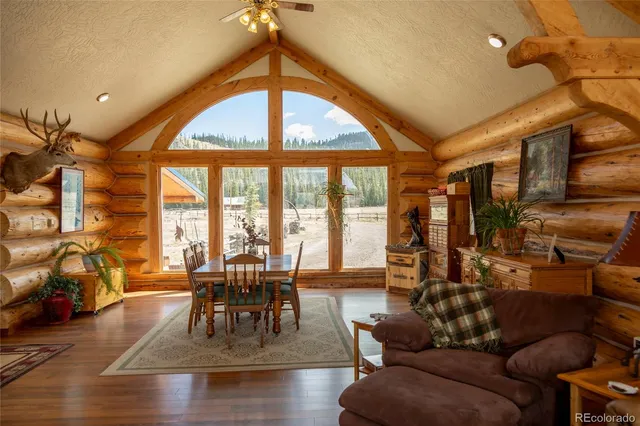 a dining room with wooden floor a chandelier a glass table and chairs
