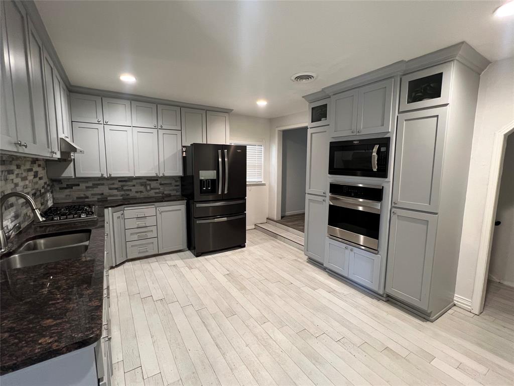 533 East Sears Street Denison, TX 75021 - Photo 6 of 27 a kitchen with granite countertop a refrigerator and a stove top oven