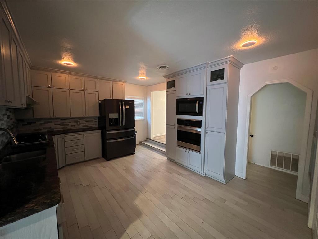 533 East Sears Street Denison, TX 75021 - Photo 10 of 27 a kitchen with granite countertop a refrigerator and a stove top oven