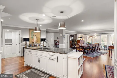 a kitchen with stainless steel appliances kitchen island granite countertop a stove and white cabinets with wooden floor