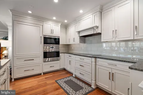 a kitchen with granite countertop white cabinets and stainless steel appliances