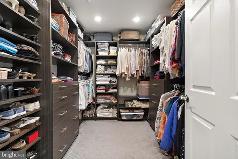 a view of walk in closet with clothes and shoes
