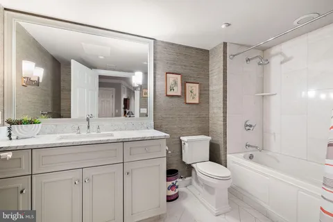 a bathroom with a toilet sink vanity granite and shower