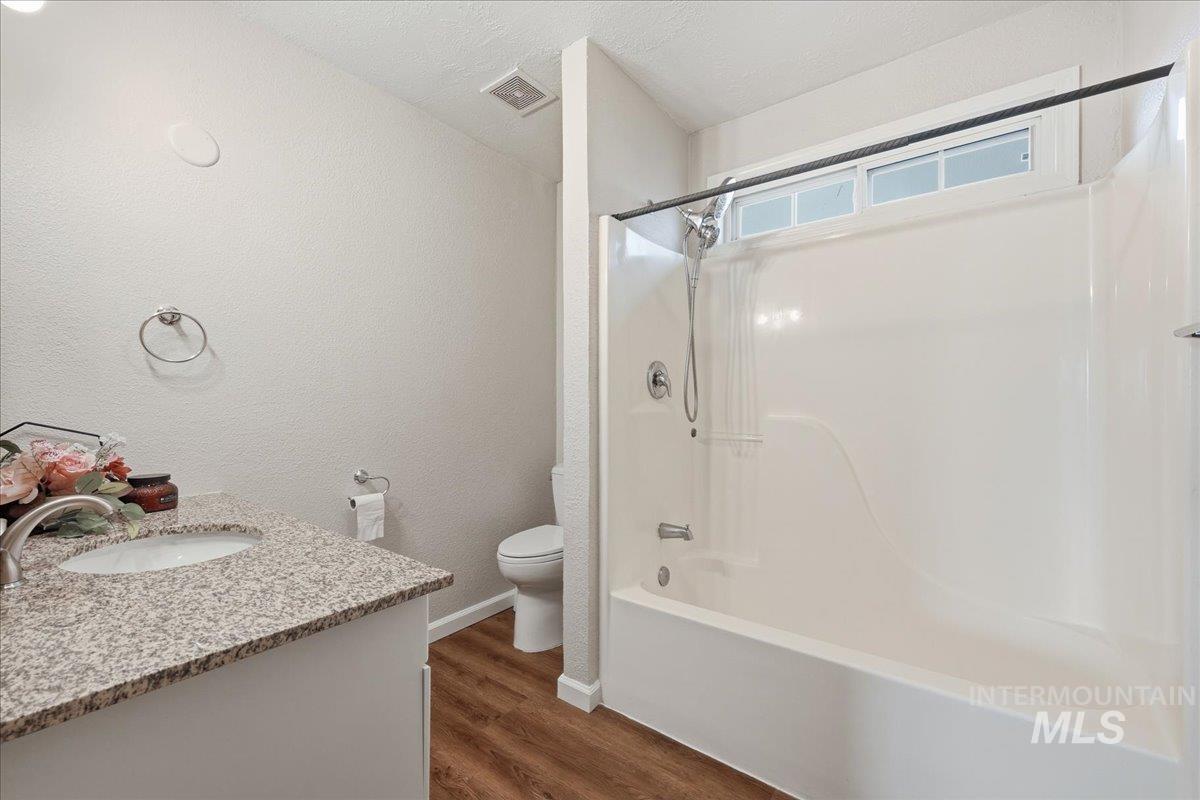 14666 Willis Road Caldwell, ID 83607 - Photo 12 of 23 Full bath featuring vanity, shower / tub combination, a textured wall, dark wood-style flooring, and a textured ceiling
