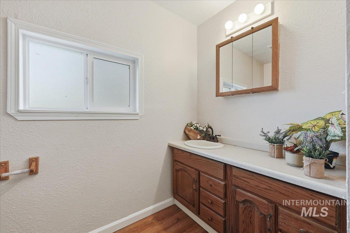 14666 Willis Road Caldwell, ID 83607 - Photo 16 of 23 Bathroom with a textured wall, vanity, and dark wood-style floors