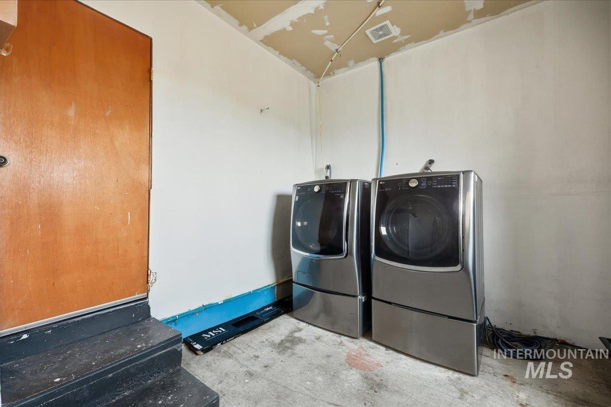 14666 Willis Road Caldwell, ID 83607 - Photo 17 of 20 Laundry area featuring washing machine and dryer and unfinished concrete flooring, water softner, storage and back door