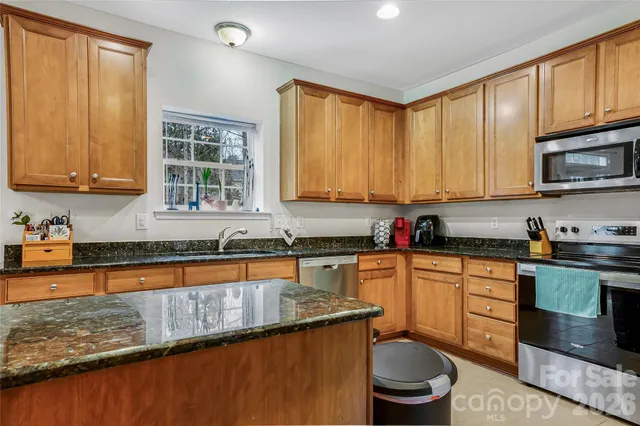 a kitchen with granite countertop a sink stove and cabinets