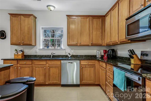 a kitchen with stainless steel appliances granite countertop wooden cabinets a sink and a stove