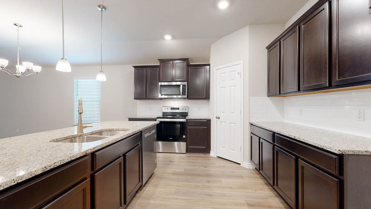405 Creekfall Road Burnet, TX 78611 - Photo 1 of 27 Kitchen with stainless steel appliances, dark wood finish cabinets, light wood finished floors, light stone countertops, and suspended lighting