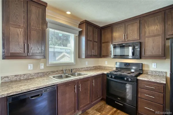 a kitchen with granite countertop stainless steel appliances a stove sink and cabinets