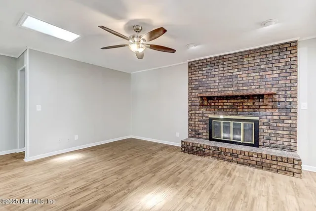 a view of an empty room with wooden floor and a fireplace