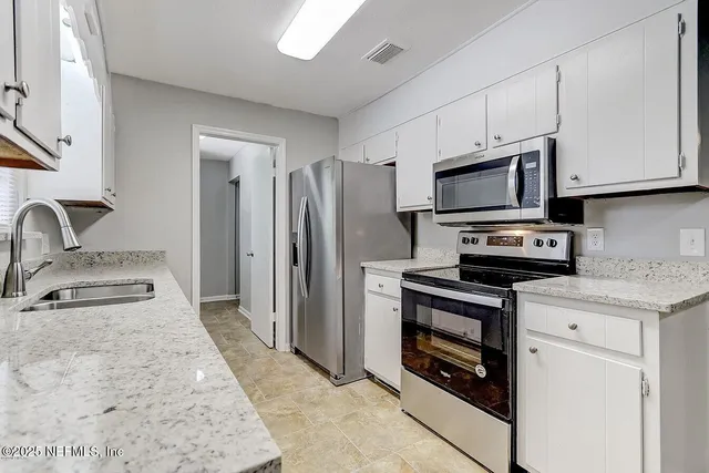 a kitchen with stainless steel appliances granite countertop a refrigerator stove and sink