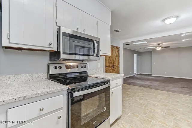 a kitchen with granite countertop white cabinets and stainless steel appliances