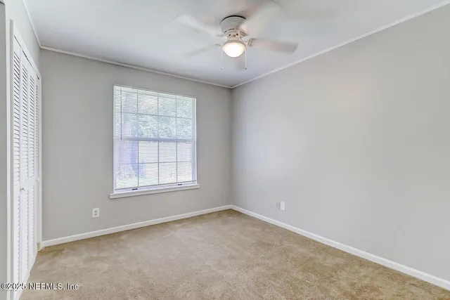 an empty room with a window and ceiling fan