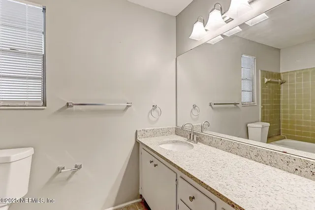 a bathroom with a granite countertop sink a toilet and a mirror
