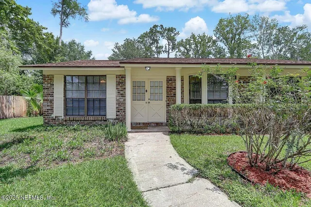 front view of a house with a yard and potted plants