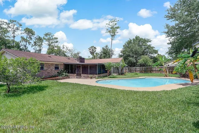 a view of pool with lawn chairs and large trees