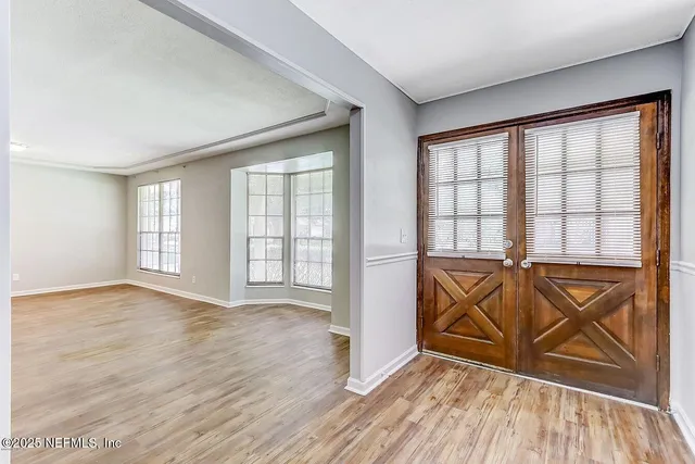 an empty room with wooden floor and windows