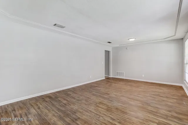 a view of an empty room with wooden floor