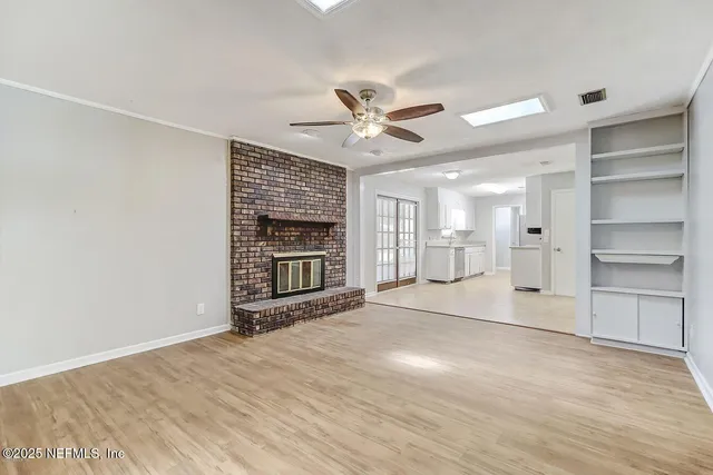 a view of an empty room with a fireplace and a window