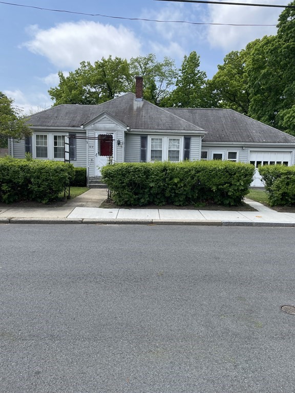 a front view of a house with a yard and potted plants