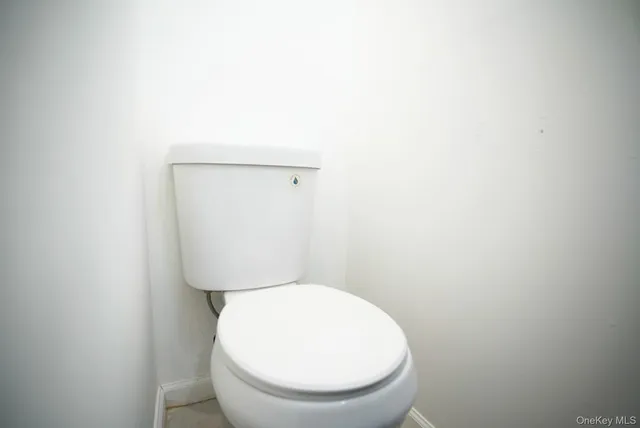 a white toilet sitting next to a white wall