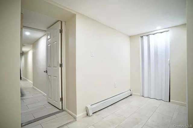 a view of a hallway with wooden floor and a bathroom