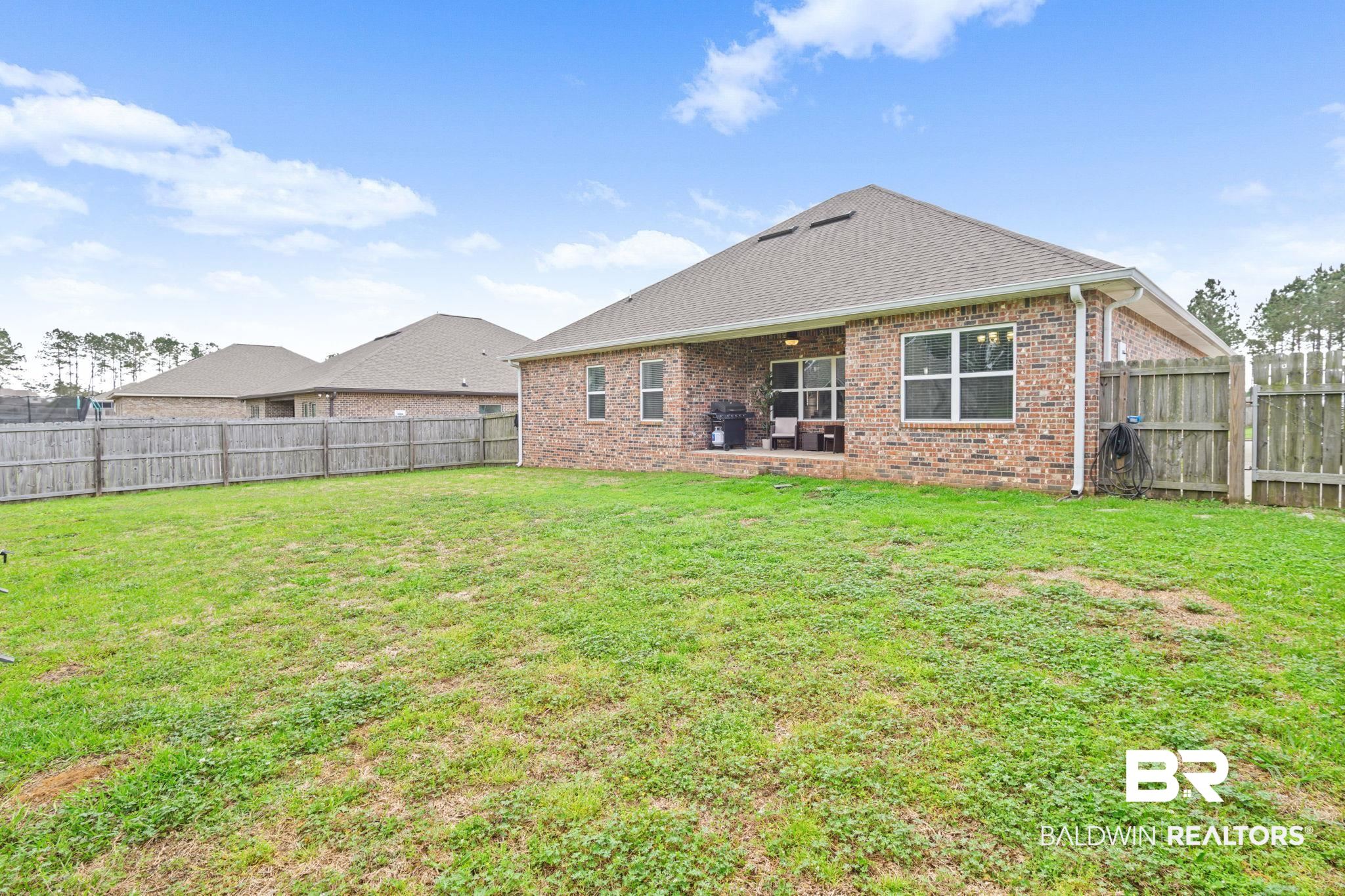 12693 Waxwing Avenue Daphne, AL 36527 - Photo 13 of 43 Back of house featuring brick siding, a patio, a fenced backyard, and roof with shingles