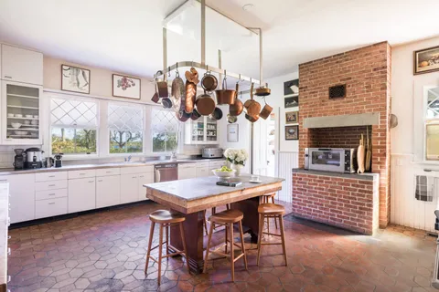 a kitchen with stainless steel appliances kitchen island granite countertop a table chairs sink and cabinets